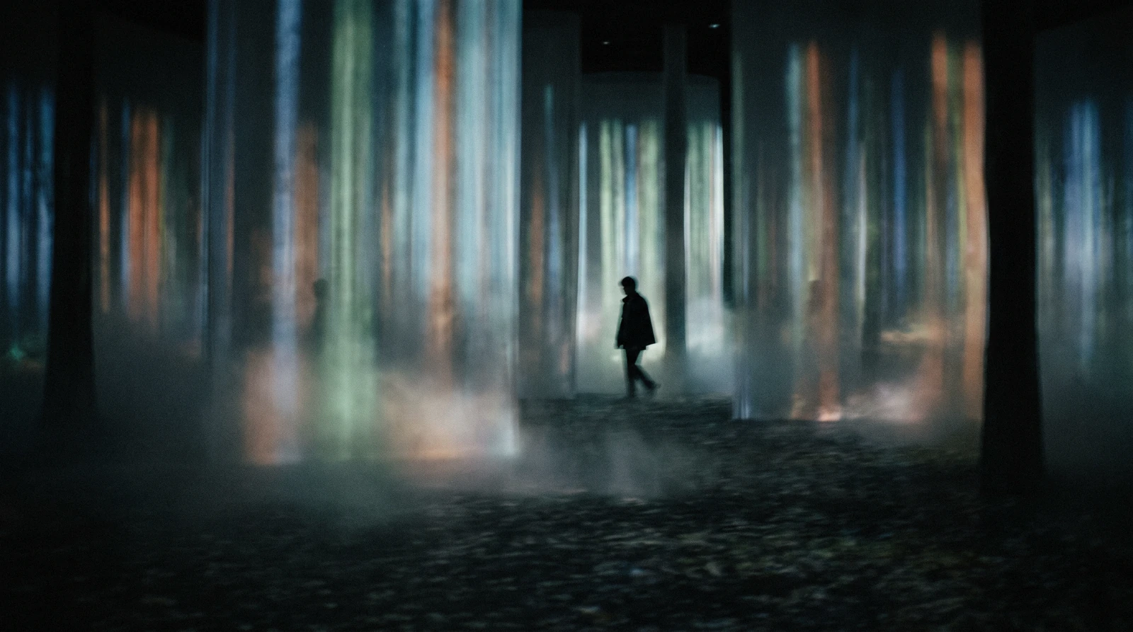 Visitors silhouetted inside a hall of hanging light sculptures with mirrored walls, teamLab Borderless Azabudai Hills Tokyo