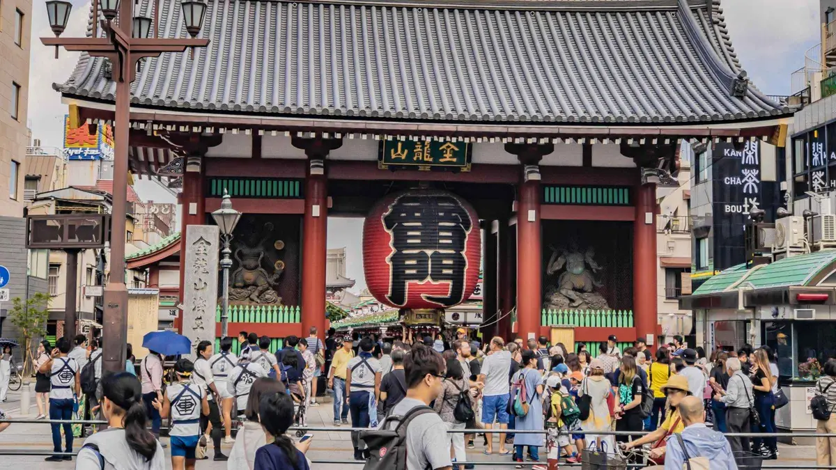Guide leading visitors past the Thunder Gate lantern into Senso-ji Temple on an Asakusa walking tour, Tokyo Japan