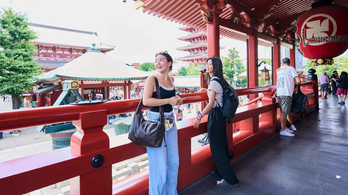 Guide and small group sampling street food near Senso-ji Temple on an Asakusa food and history walking tour, Tokyo Japan